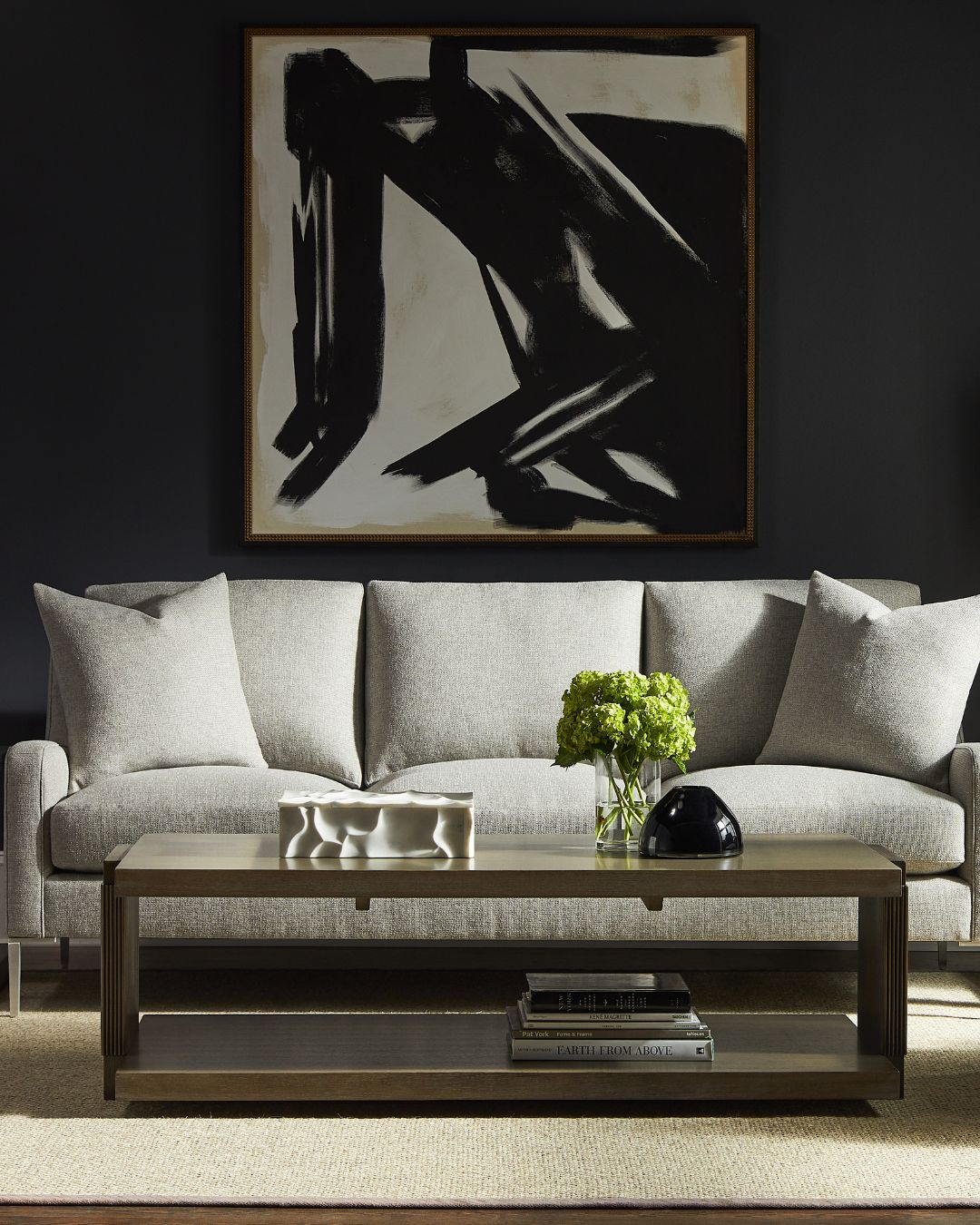 Modern living room with a gray sofa, wooden coffee table, and abstract art on the wall.
