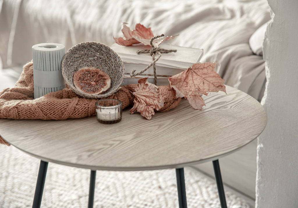 Round wood coffee table styled with two white cups and a glass vase in a cozy living room setting.