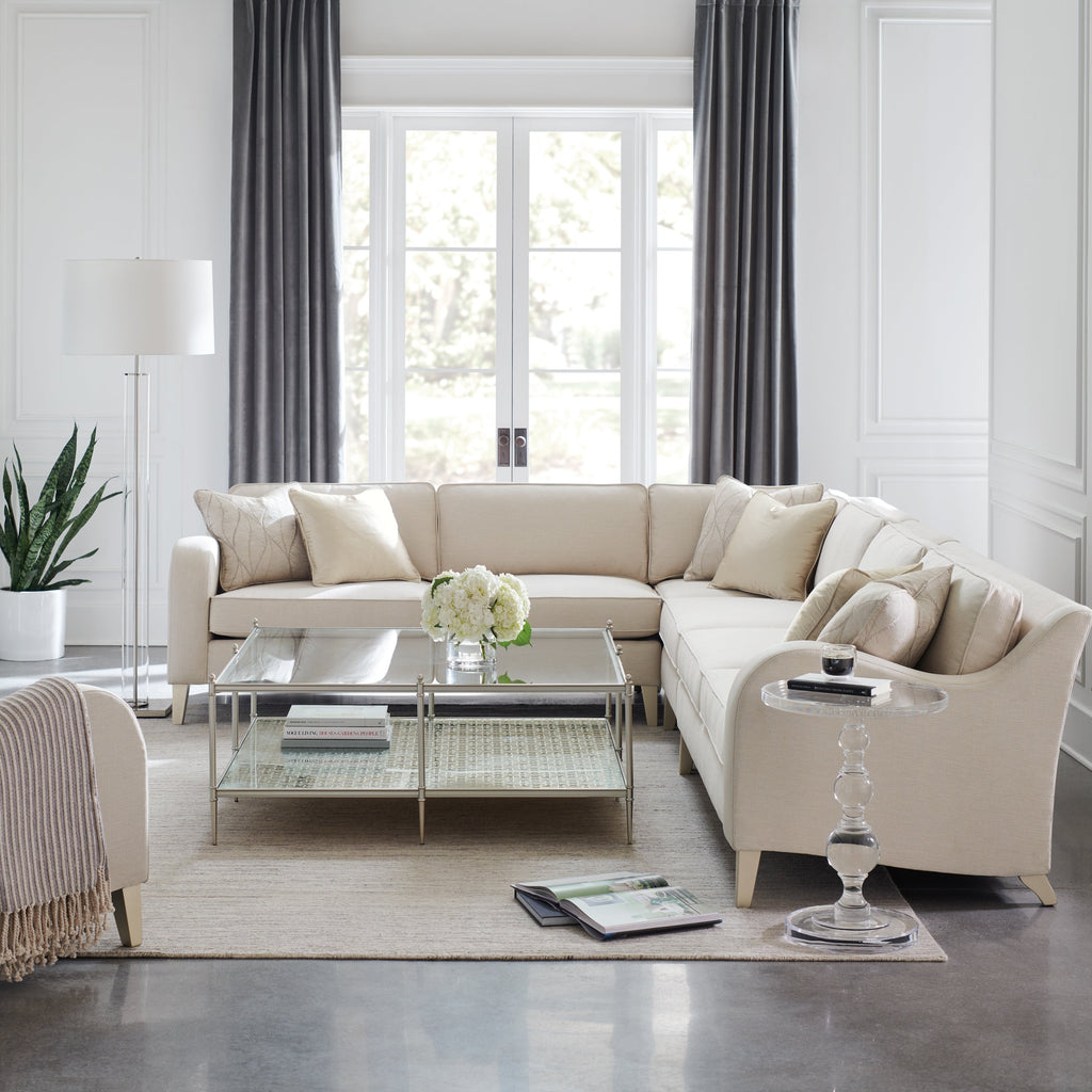 Chic silver and white sectional sofa with a large glass and metal cocktail table.