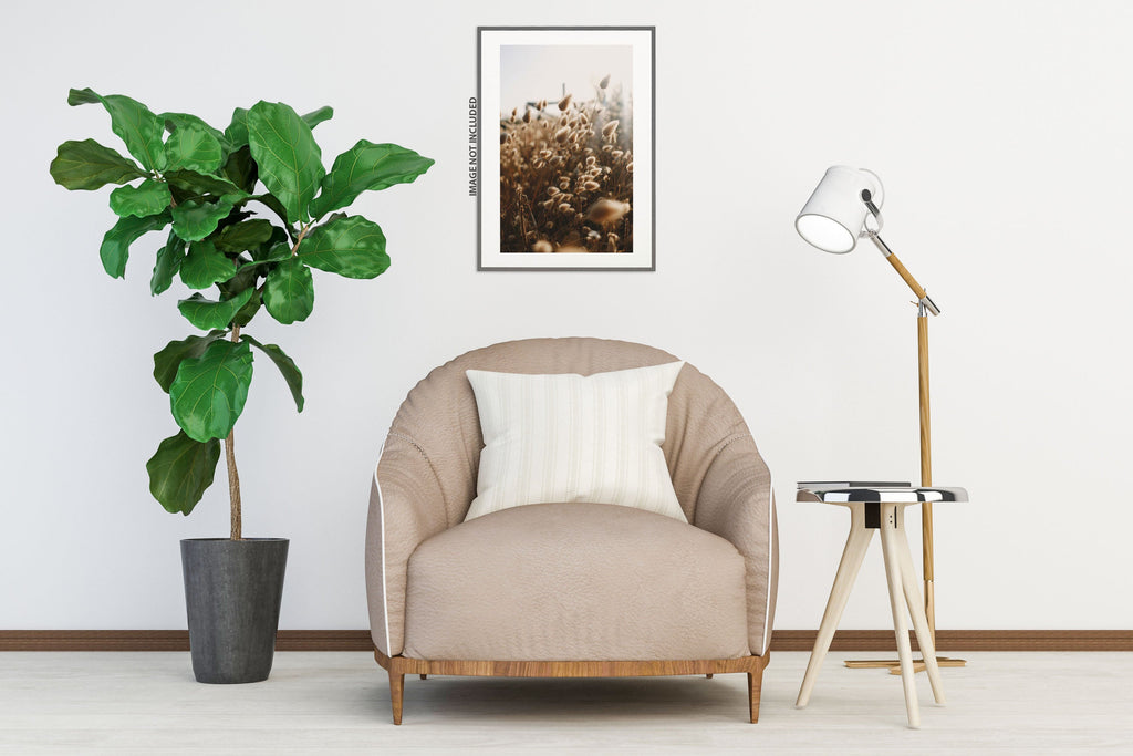Rounded barrel accent chair in blush beige fabric with a wood base, styled in a minimal white living room with a fiddle leaf fig and tripod floor lamp.