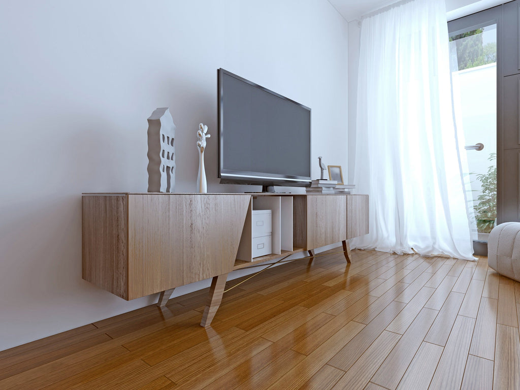 Scandinavian-style TV stand in light oak with angled tapered legs, mixed open and closed storage, supporting a flat-screen TV in a bright white room