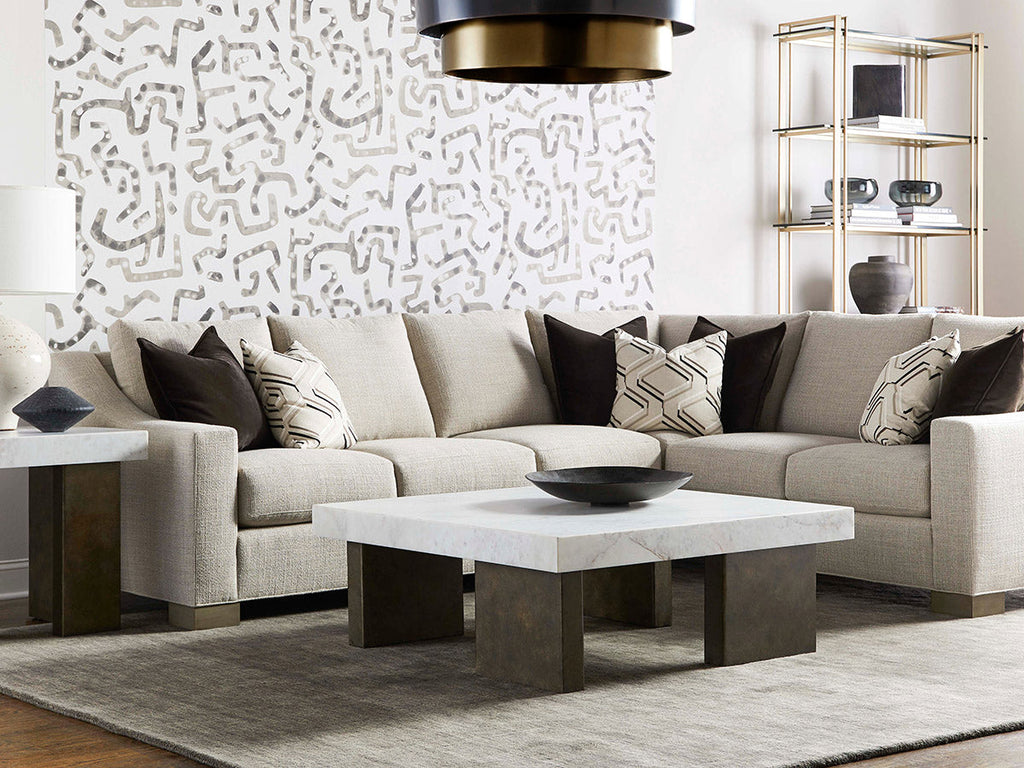 Contemporary L-shaped sectional sofa in beige linen with dark throw pillows, marble coffee table, and gold-frame etagere in a modern living room.