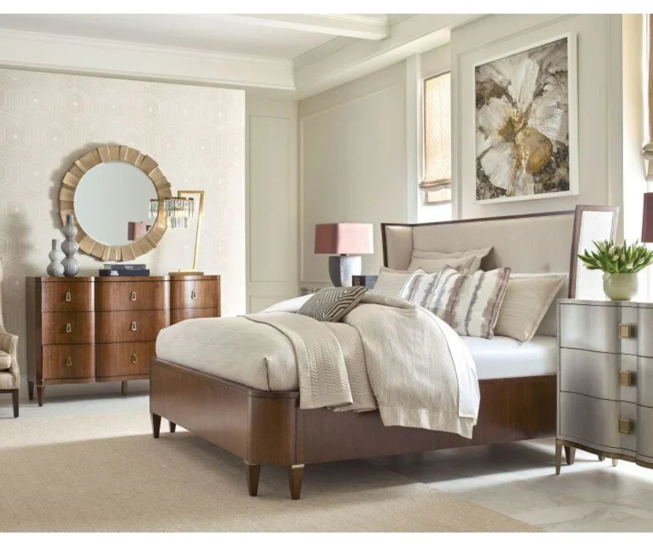 Transitional master bedroom with walnut upholstered panel bed, cream linen headboard, walnut six-drawer dresser with brass pulls, sunburst gold mirror, and silver mirrored nightstand