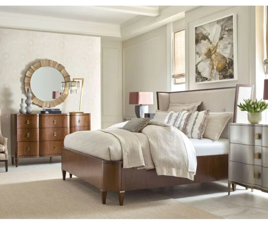 Transitional master bedroom with walnut upholstered panel bed, cream linen headboard, walnut six-drawer dresser with brass pulls, sunburst gold mirror, and silver mirrored nightstand