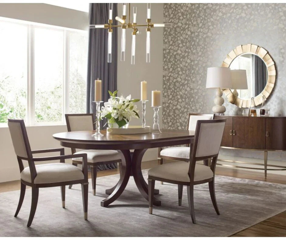 Elegant dark walnut round pedestal dining table with cream upholstered dining chairs, silver candelabras, and floral centerpiece in a transitional dining room with botanical wallpaper