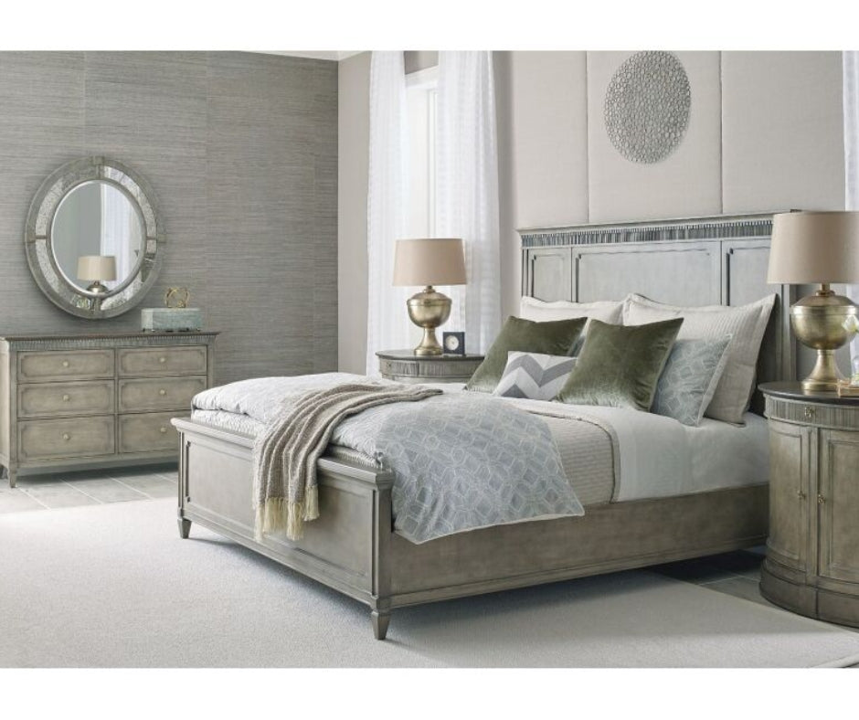 Gray traditional bedroom set with panel bed, matching dresser, nightstands, and round mirror, styled with green velvet pillows and gold table lamps.