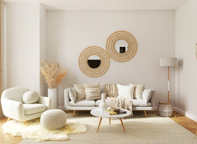 Bohemian living room with rattan wall mirrors, neutral linen sofa, woven pouf, and pampas grass decor.