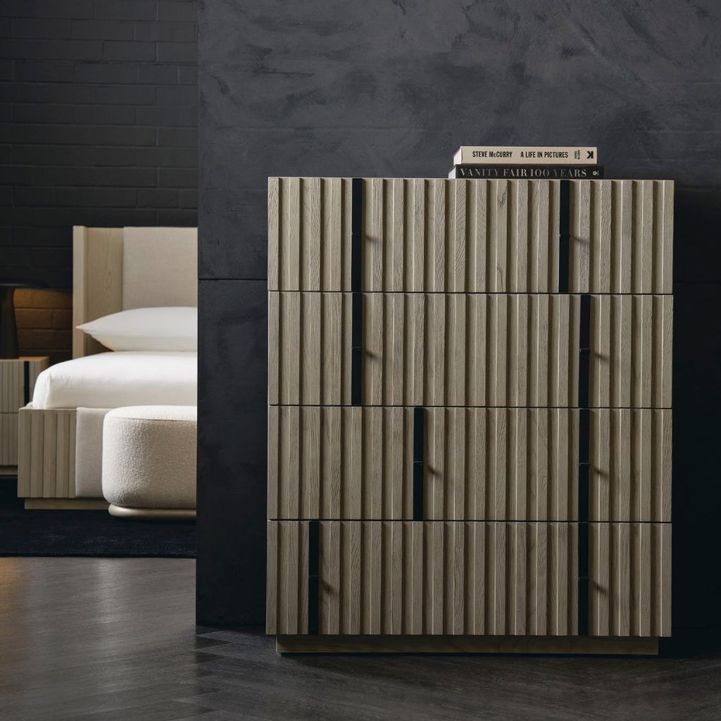 Wooden dresser with a dark wall and bed in the background