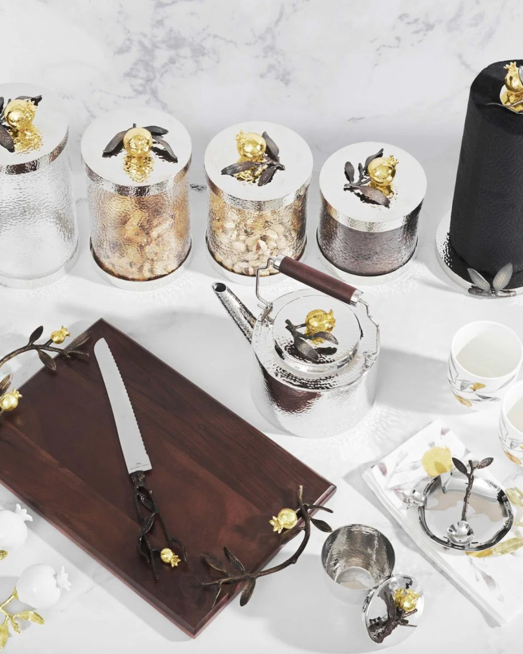 Table setting with decorative items including a teapot, knives, and small containers on a marble surface.