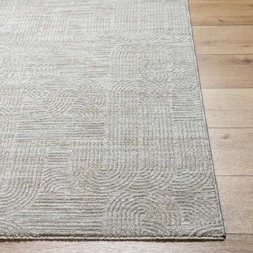 A close-up of a textured area rug with a light beige and gray geometric pattern, shown on a light wood floor.