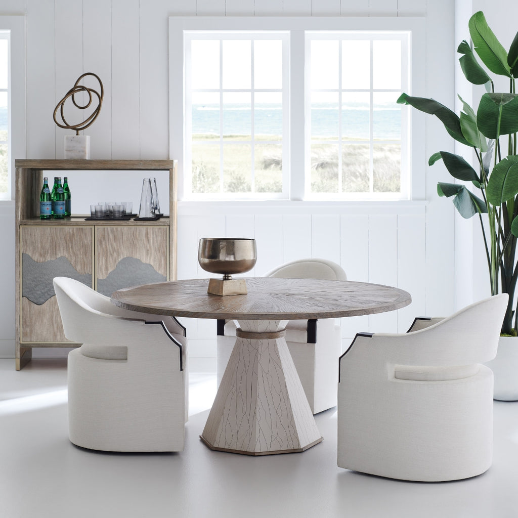 Modern dining area with a round wooden table and white chairs in a bright room.