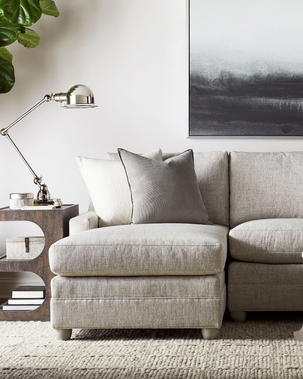 Gray sectional sofa in a living room with a lamp, side table, and abstract painting.