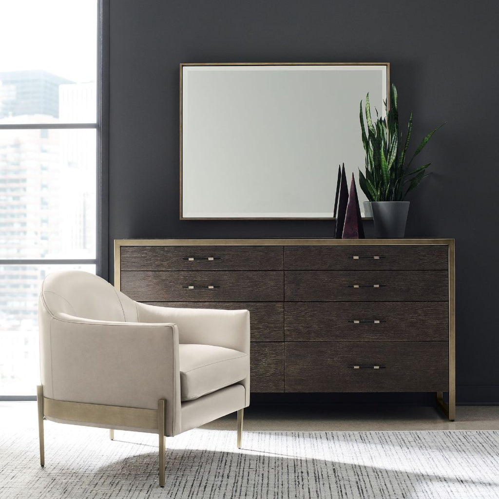 Modern bedroom with a dark wood dresser, beige armchair, and large mirror.