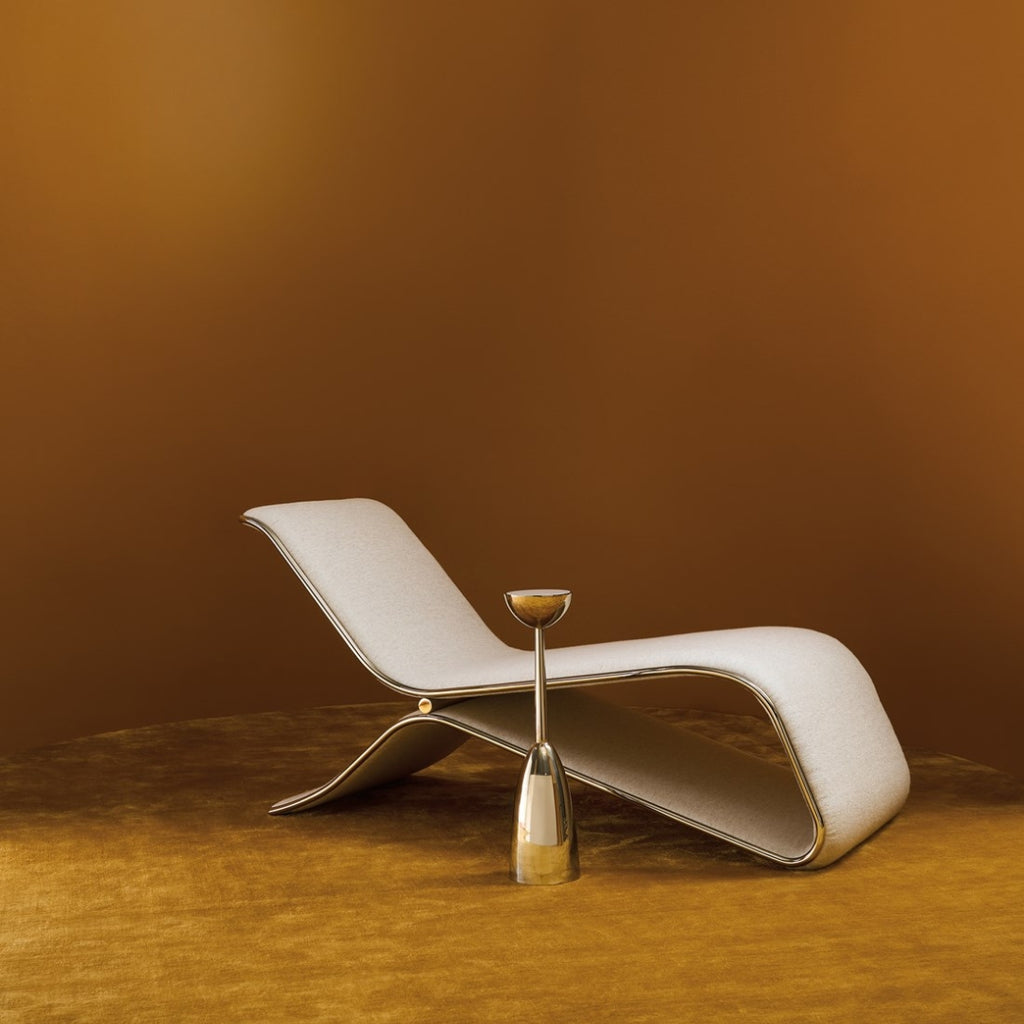 Modern white lounge chair with a gold side table against a brown background