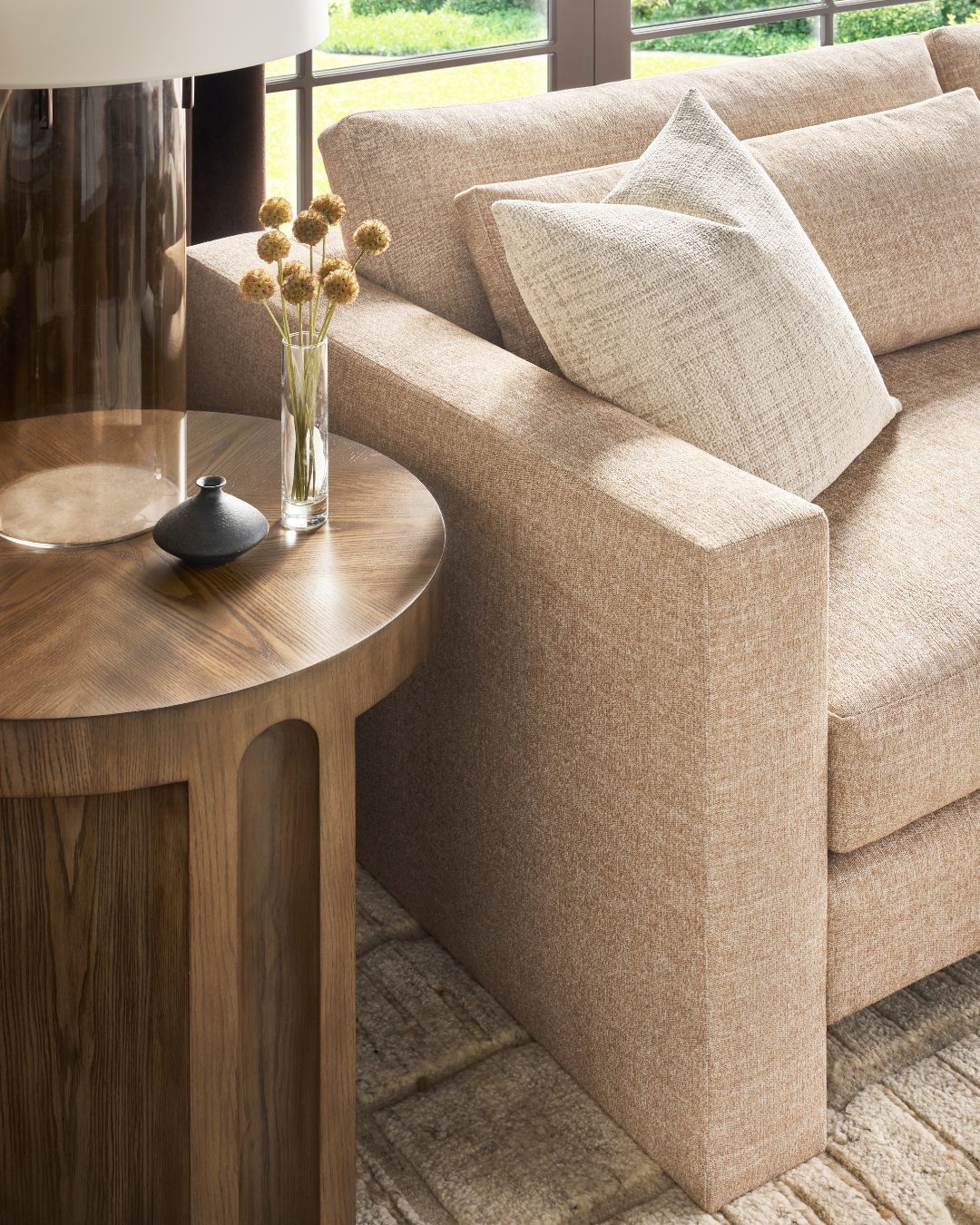 Beige sofa with a wooden side table and decorative items in a living room setting.