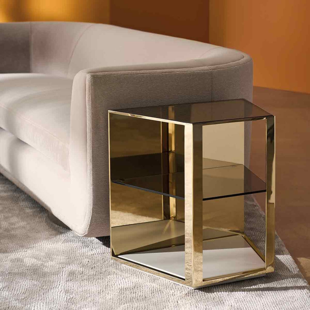 Gold side table next to a gray sofa in a room with orange walls.