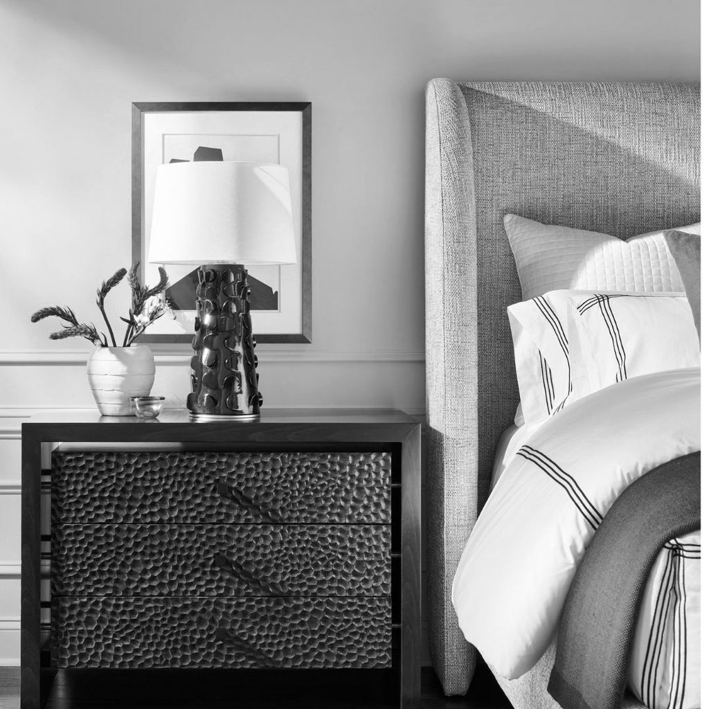 Bedroom with a nightstand and bed featuring decorative elements.