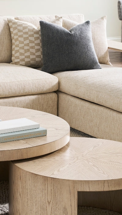 Beige sectional sofa with cushions and a wooden coffee table in a living room setting.