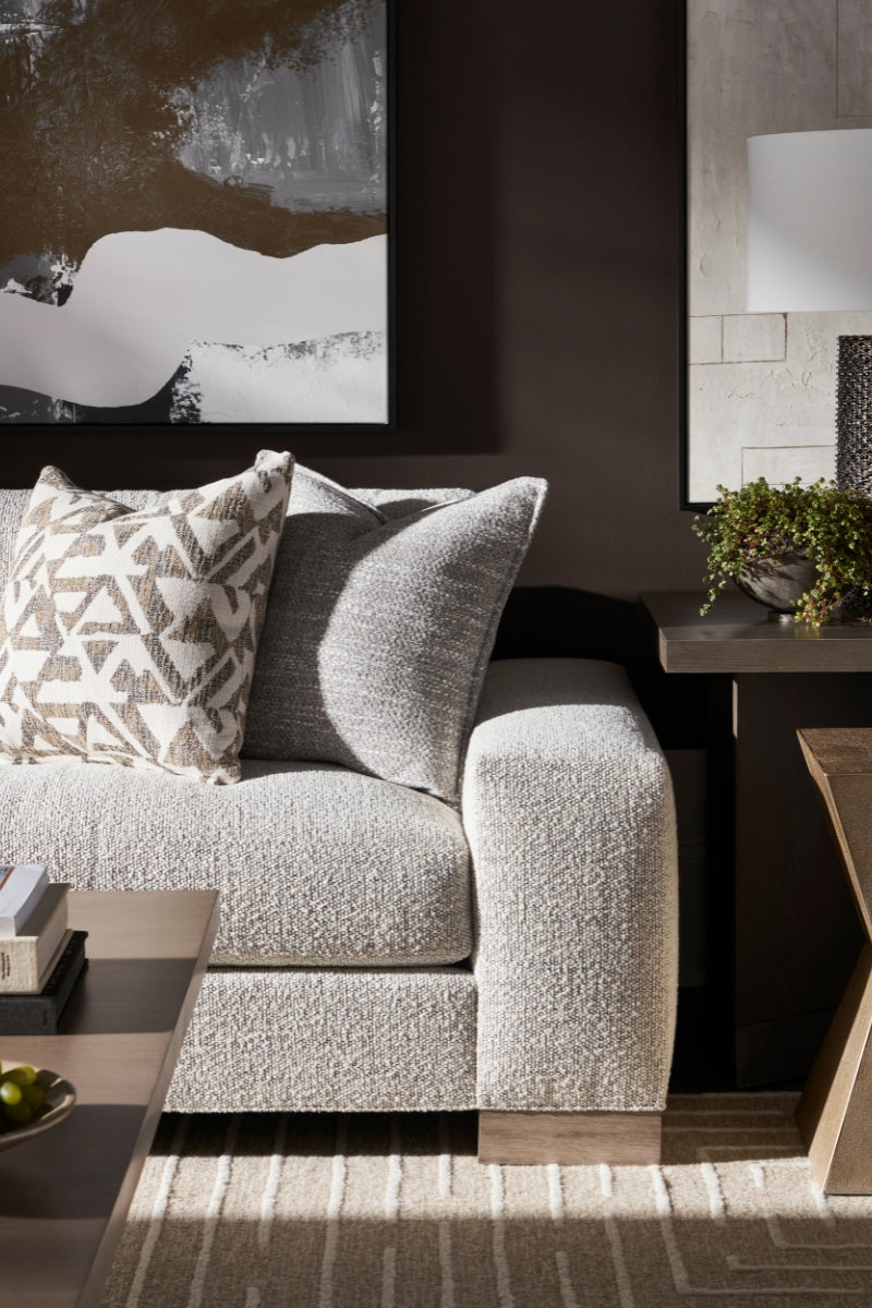 Contemporary grey sofa with patterned cushions in a room with abstract art and a metal lamp.