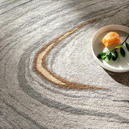 Orange and green leaves on a white plate with sand and water creating a wave pattern