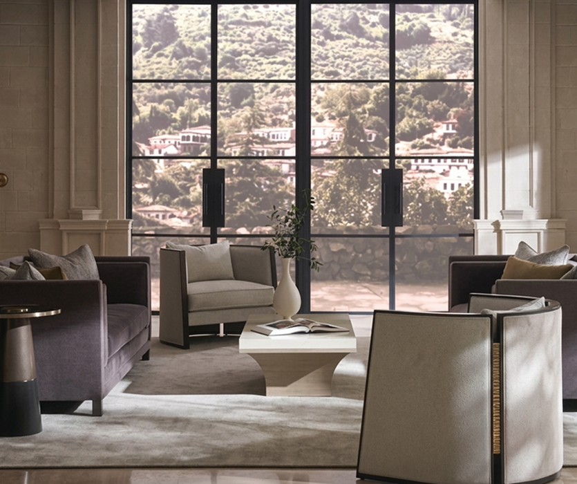 Living room with floor-to-ceiling windows, a light sofa, a low table, and armchairs arranged to take in the view of the outdoors