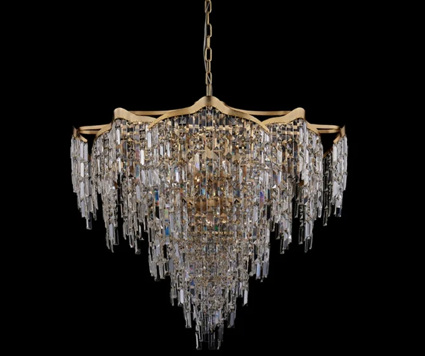 A gold chandelier with layered tiers of hanging crystal drops on a black background