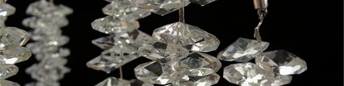 A cascading crystal chandelier drops against a dark background in the Mobilart showroom