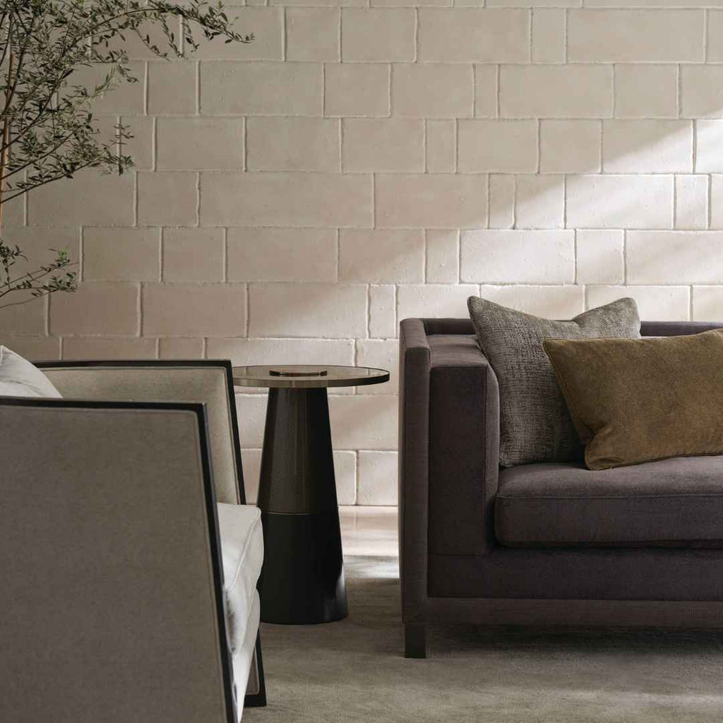 Grey linen sofa with olive and taupe throw pillows beside black metal side table
