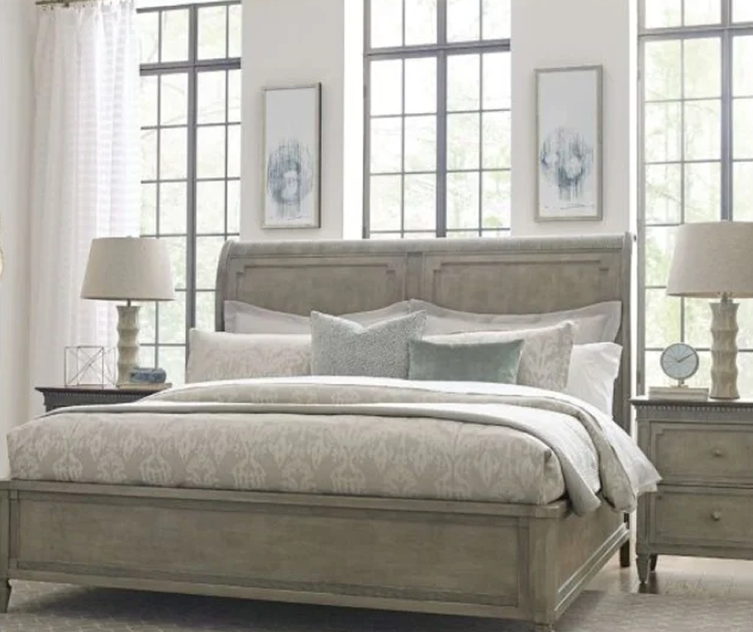 Bed frame in weathered grey wood with a paneled headboard and a matching nightstand, photographed against a plain light background