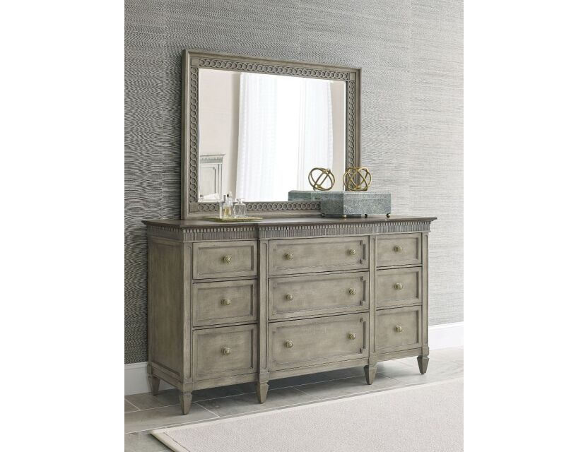 Commode double grise à neuf tiroirs avec miroir mural rectangulaire à détail corde et quincaillerie en laiton dans une chambre de style transitoire.